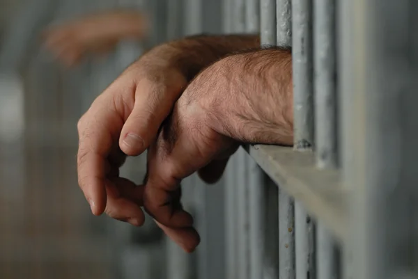 Mans hands behind bars in jail — Stock Photo, Image