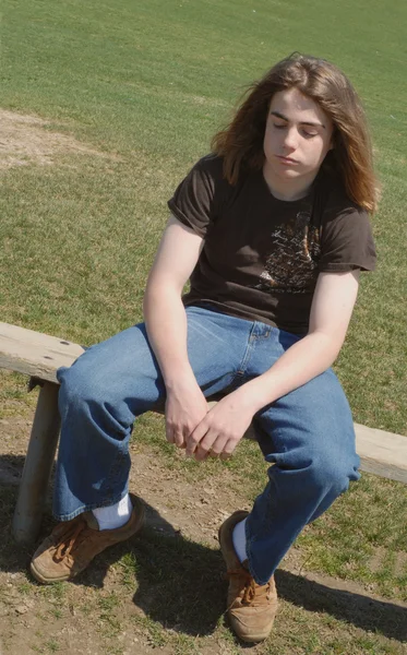 Thirteen year old teenager sulking as though isolated from school friends — Stock Photo, Image