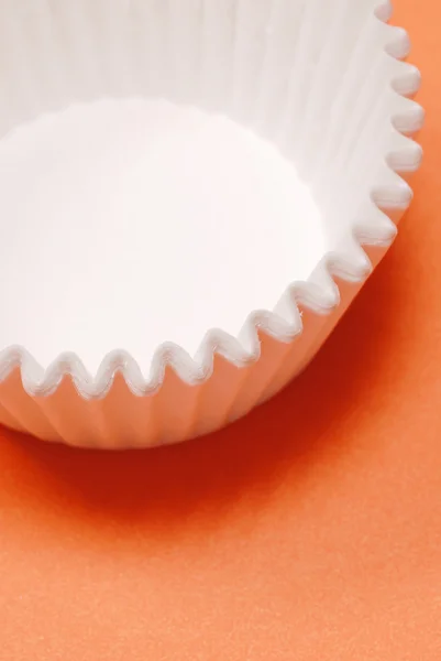 Weiße Muffin Tassen auf leuchtend orangefarbenem Hintergrund — Stockfoto