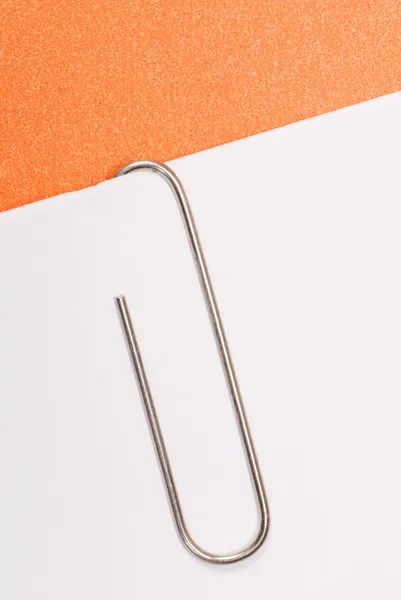 Paperclip vastgemaakt op wit papier met oranje achtergrond — Stockfoto