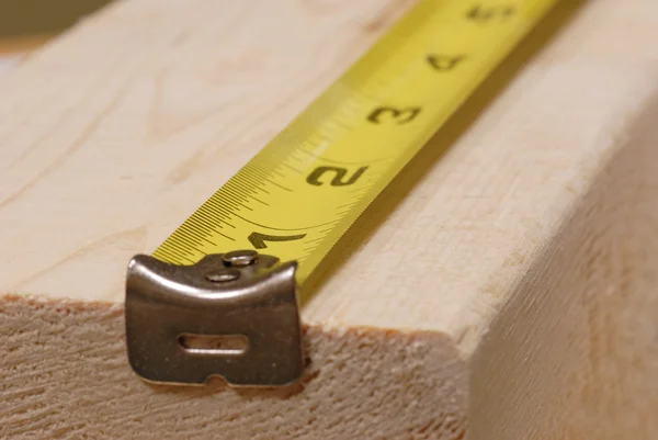 Measuring tape lined up ready to measure piece of wood — Stock Photo, Image