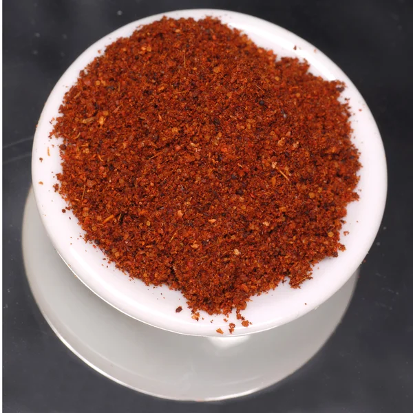 Chili powder in white dispenser on black background — Stock Photo, Image