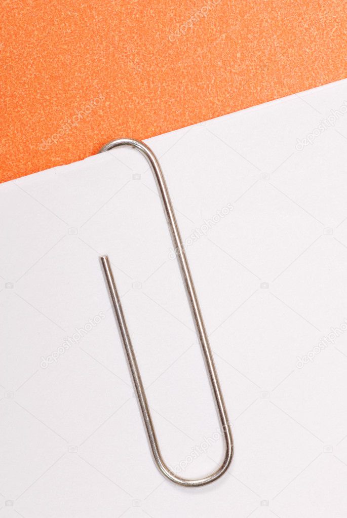 paper clip fastened to white paper with orange background
