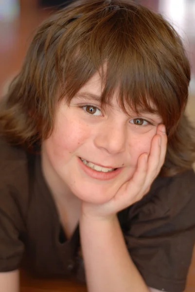 Good looking boy age 12 smiling with chin resting in hand — Stock Photo, Image