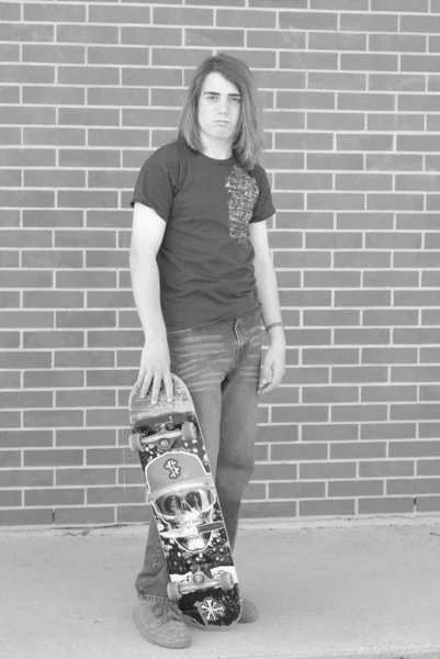 Teenage boy with skateboard displaying attitude of skateboarding culture — Stock Photo, Image