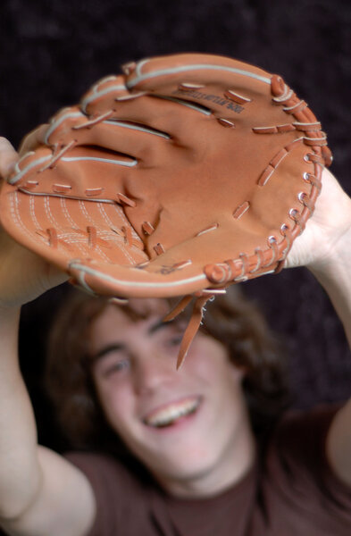 teenager reaching out to catch baseball with shallow depth of field