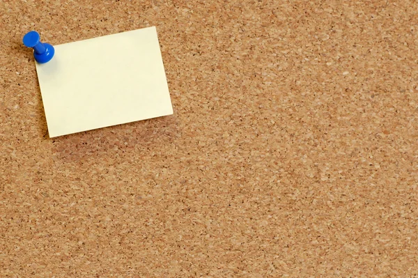 cork board with blank note attached with thumb pin