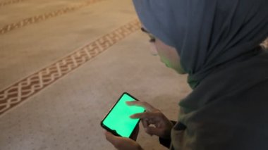 Krom anahtar, camide yeşil ekran akıllı telefon arayan Müslüman kadın.