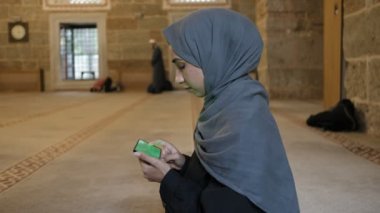 Müslüman kız, İslami camide yeşil ekran akıllı telefon kullanıyor.