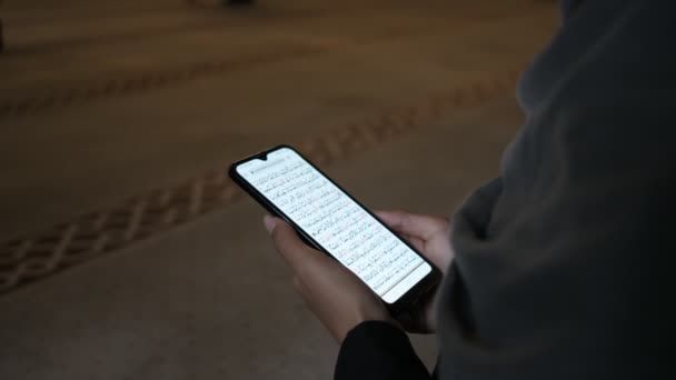 Διαβάζοντας Holly βιβλίο στο τζαμί, νεαρή μουσουλμάνα γυναίκα ανάγνωση Quran smartphone — Αρχείο Βίντεο