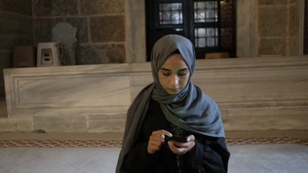 이슬람 교인 여자가 이슬람 사원에서 스마트 폰으로 코란을 읽고 있는 모습 — 비디오
