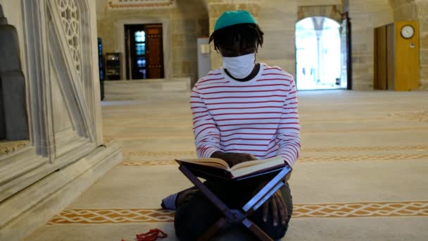 Läsa Koranen, afrikansk ung man mask läser Koranen — Stockvideo