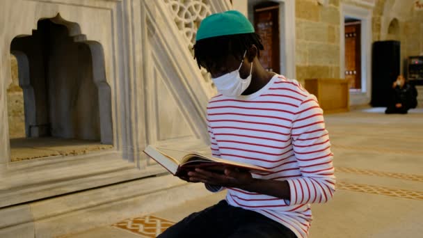 Kara Adam Maskeli Kuran, Siyah genç adam maskesi Kur 'an okuyor — Stok video