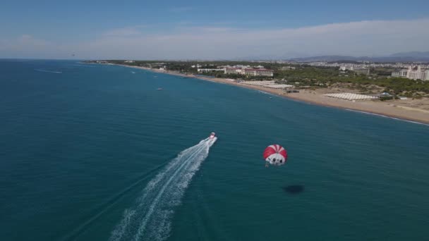 Zdjęcie lotnicze parasailingu na plaży z łodzią — Wideo stockowe