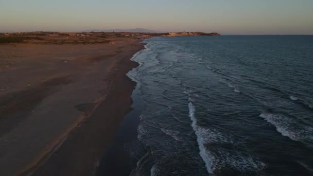 Zonsondergang reflecterend op golven en kust — Stockvideo