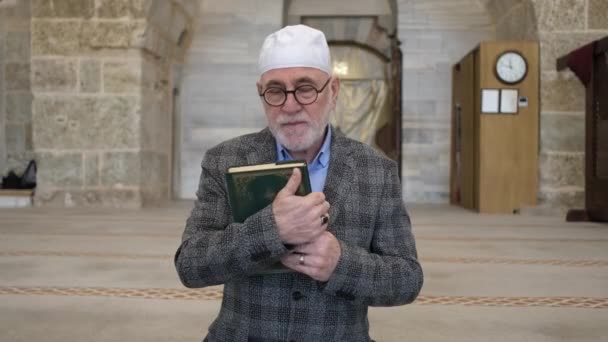 Stary człowiek trzymający Koran — Wideo stockowe