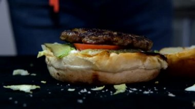 Katmanlı hamburgerin yavaş çekimi, domates peynirli hamburger menüsü görüntüsü, lezzetli hamburgerler, izole edilmiş fast food yemeği görüntüsü.