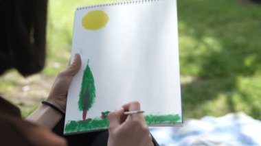 Yeşil parktaki tuvale çizilmiş resim, kırmızı şapkalı kadın tuvale agar boyuyor, açık havada resim yapıyor, yağlı boyayla beyaz tuvale resim yapıyor. 