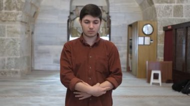 Müslüman elini kaldırıyor ve takbir diyor, namaz kılmak için takbir demesi gereken adam, namaz kılma kurallarına göre camide ibadet ediyor.