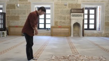 Müslüman bir adam camide namaz kılar, diz çöker, ruku okur, İslam kurallarına göre dua eder, camide ibadet eder.