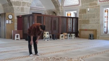 Müslüman bir adam camide namaz kılar, diz çöker, ruku okur, İslam kurallarına göre dua eder, camide ibadet eder.