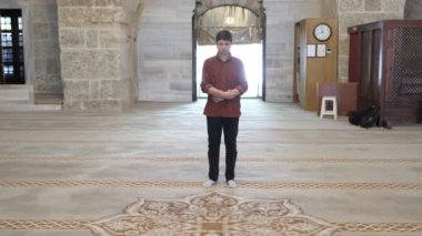 Genç Müslüman adam büyük caminin içinde ibadet eder, ibadet kurallarına göre secde eder, dini İslam 'a tapınma kurallarına göre yaşar