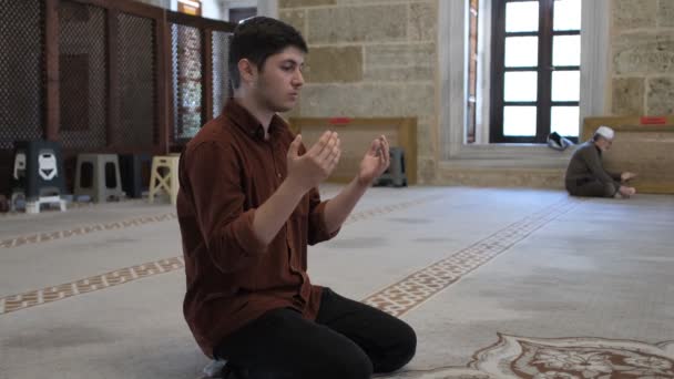 穆斯林年轻人高举双手在清真寺里祈祷 看到年轻人希望在清真寺里敬神 按照伊斯兰教义祈祷 — 图库视频影像