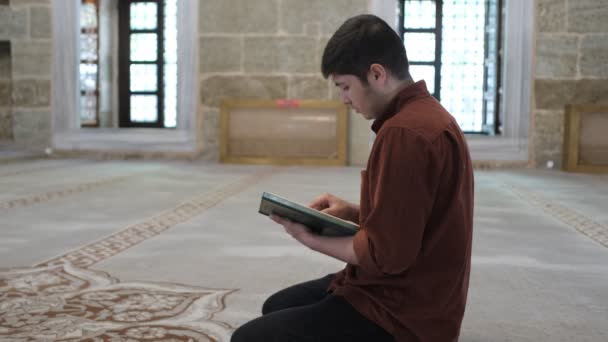 Cami Içinde Diz Çöküp Kuran Okuyan Bir Gencin Resmi Elinde — Stok video
