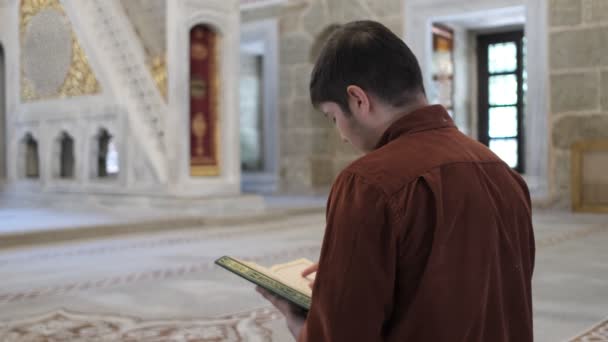 モスクの中に座っている間にクルアーンを朗誦する若者の背中から撮影された画像 — ストック動画