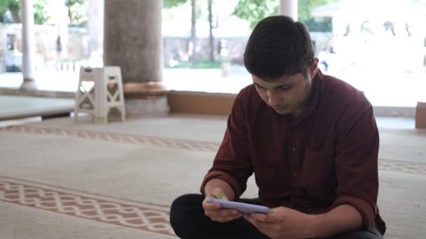 男人跪在清真寺里看着他的手机 用绿色屏幕手机的应用程序 在清真寺里用伊斯兰式应用程序 — 图库视频影像