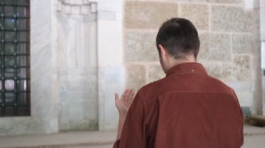 Müslüman genç adam ellerini açıp Tanrı 'ya dua ediyor, avuçlarını gökyüzüne kaldırıyor, Tanrı' dan af diliyor, İslam kurallarına göre bir dilek diliyor.