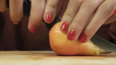 Armudu bıçakla keserken yakın plan görüntü, armut meyvesini ikiye bölen bıçak tutan kadın, taze tematik meyve görüntüsü.