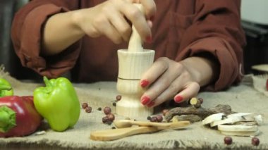 Female hand pounding the spices, image of woman hand beating spices in wooden pestle, crushing spices with nature theme, nature products theme indoors