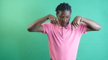 Siyah adam ekranın altını işaret ediyor, genç siyah adam iki eliyle ekranı işaret ediyor, yeşil ekranın önünde vücut dilini ve yüz ifadelerini gösteriyor.