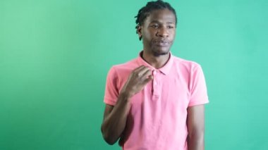 Image of black man trying to cool off feeling very warm, man body language expression feeling warm, image of emotions and facial expressions taken in front of the green curtain