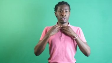 Black man feeling very hot, body language expression of black man trying to cool off with his hands, image of emotions and facial expressions taken in front of the green curtain