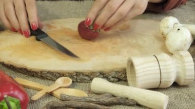 Tahta sunum tahtasında kırmızı çilekleri dilimleme resmi, kadın çilekleri ikiye bölme, tematik taze meyve hazırlama, ahşap sunum tabağında dilimleme işlemi