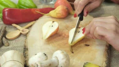 Armutları servis tabağında bıçakla kesme, tematik bir doğal ürün masasında meyve kesme, ahşap sunum tabağında kesme.