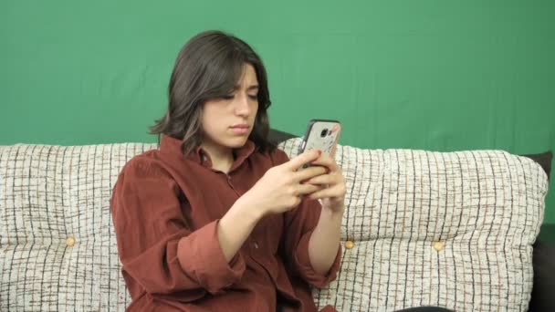 Young Woman Sitting Sofa Looking Phone Bored Face Expression Facial — Αρχείο Βίντεο