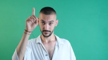 Man pointing with ones finger, show the top corner of the screen with one finger, emotions and facial expressions of the model in front of the green screen