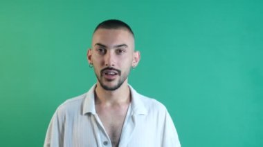 Erkek jest yapıyor, şaşırmış bir ifadeyle erkek model, yüz ifadeleri resmi yeşil ekranın önünde çekilmiş.