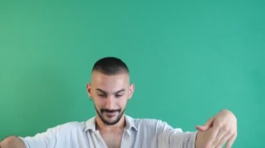 Dans eden adamın zaman aşımı, beyaz tişörtlü adamın jestleri dans ederken eğlenmesi, yüz ifadeleri görüntüsü yeşil ekran önünde çekilmesi.