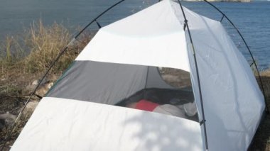 Man waking up in tent, view of young camper waking up in tent, male vacationing in tent, summer vacation in tent with sea view