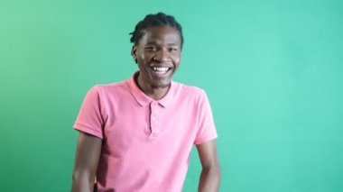 Pembe tişörtlü genç adamın gülüşü, erkek modelin mutlu bir şekilde gülen görüntüsü, yeşil ekran önünde vücut dilini ve yüz ifadelerini göstermesi.