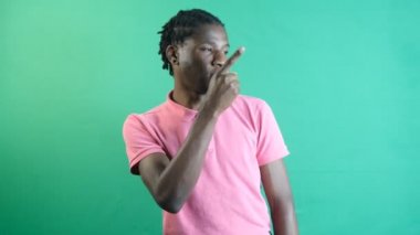 Man points left corner of screen, black teenager pointing to the left of the screen with his left hand, show body language and facial expressions in front of a green screen