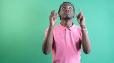 Genç adam parmakla işaret ediyor, siyah genç iki eli ekranın üstünde, yeşil ekranın önünde vücut dilini ve yüz ifadelerini gösteriyor.