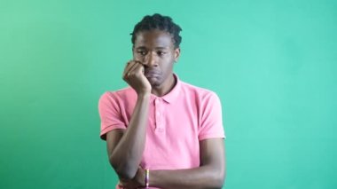 Black mans overthinking facial expression, models solitary thinking gestures, image of emotions and facial expressions taken in front of the green curtain