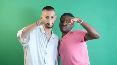 Two men handshake, friends special greeting gesture, men show to posing funny, two male models posing for camera, image of emotions and facial expressions taken in front of the green screen