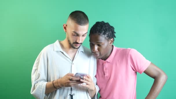 Telefonda Eğlenceli Şeyler Izleyen Iki Erkek Arkadaş Yeşil Ekranın Önünde — Stok video