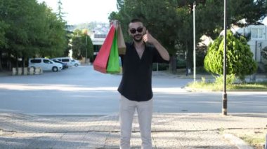 Shopping is happiness message, young man showing like sign by showing the bags in his hand, young man showing his happiness back from shopping